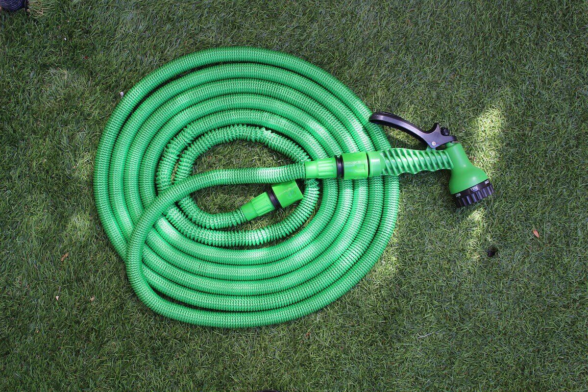 צינור השקיה מתכווץ מונח על דשא גינת הבית